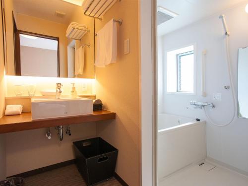 Hasami波佐见极乐别墅酒店的一间带水槽、浴缸和镜子的浴室