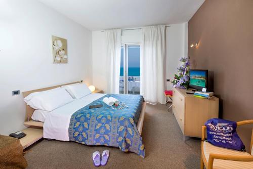 阿尔巴·阿德里亚蒂卡Hotel & Residence Medi Garden的一间卧室配有一张床、一台电视和一把椅子