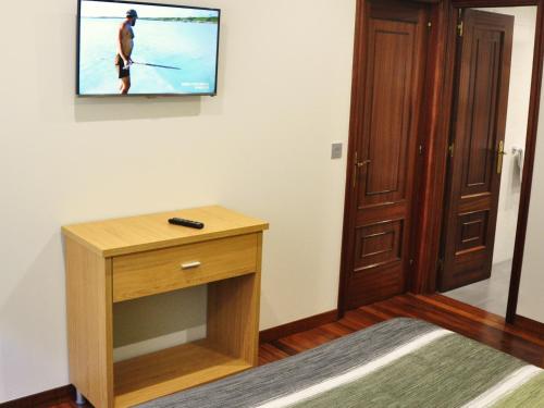 贡多马尔帕斯旅馆的一间墙上配有电视的房间,配有桌子
