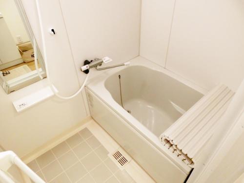 名古屋Guesthouse TOHO的浴室设有白色浴缸及镜子
