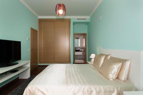 拉戈斯Porto de Mos Golf & Beach B&B AL-40312的卧室配有白色的床和电视。