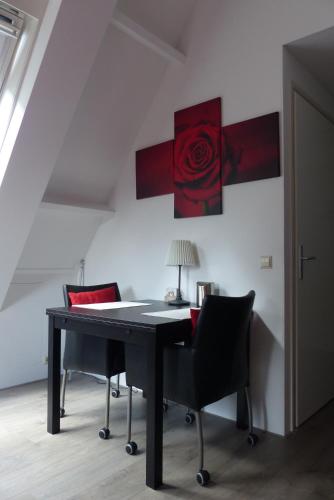 迪伦旺德尔德罗德波克住宿加早餐旅馆的一张桌子,椅子和墙上的红玫瑰