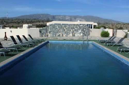 Dār SawdāʼJebel Shams Resort منتجع جبل شمس的一座带椅子的大型游泳池和一座建筑