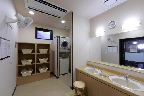 仙台森带祖米路特因特酒店的一间带两个盥洗盆的浴室和一台电视