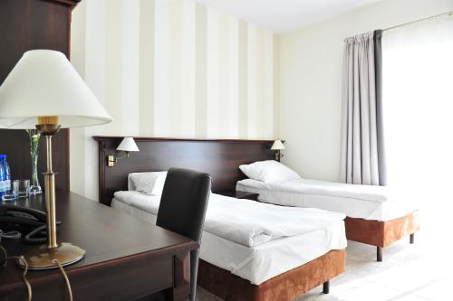 奥克宁卡Hotel Biały Dwór的酒店客房配有两张床和一张带台灯的书桌