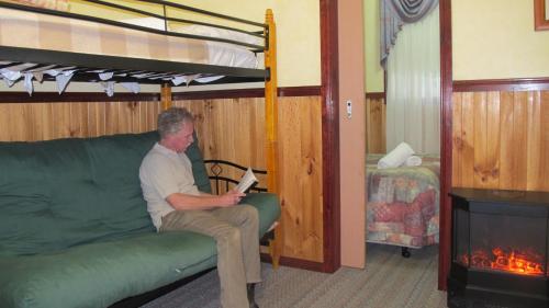 维多利亚山雪松山林小屋的坐在一张沙发上的人,坐在一个配有双层床的房间