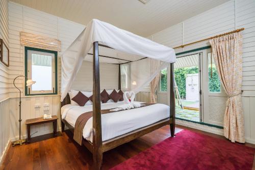 暖武里府KALANAN Riverside Resort former Buddy Oriental Riverside的一间卧室配有一张带天蓬的床
