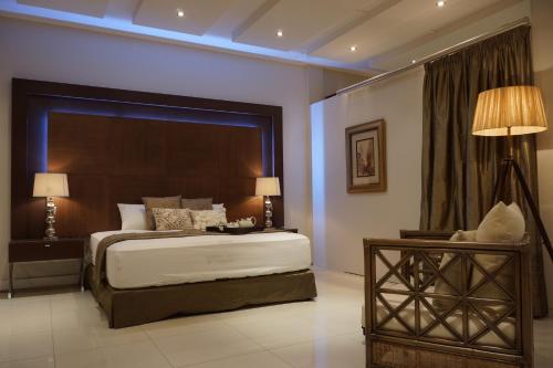马普托2001酒店的一间卧室配有一张大床、一张桌子和台灯。