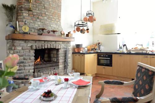 马斯特里赫特Artagnan的一间带砖砌壁炉和桌子的厨房以及一间带餐桌的厨房。