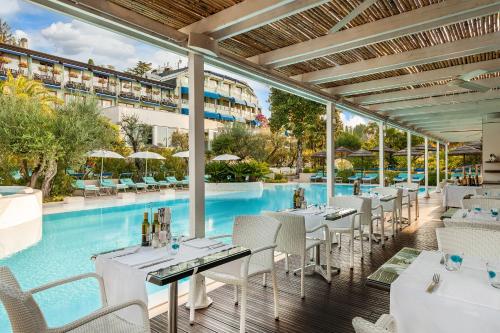 西尔米奥奈Olivi Hotel & Natural Spa的餐厅设有一座带桌椅的游泳池