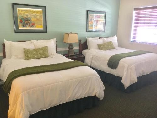 亨廷顿Whitman Motor Lodge的一间卧室设有两张带白色床单的床和窗户。