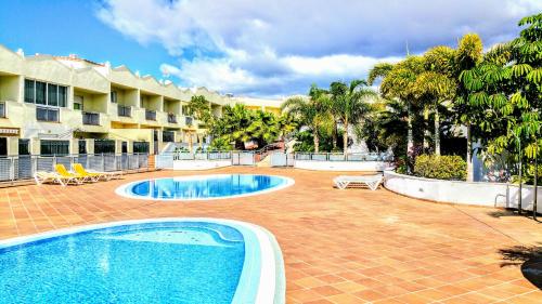 阿德耶Townhouse Costa Adeje的一个带游泳池的庭院和一个度假村