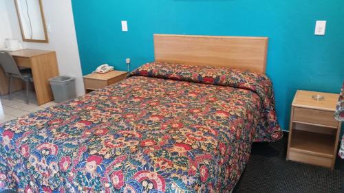 西尔马经济汽车旅馆的一间卧室配有一张带五颜六色棉被的床