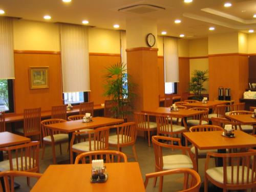 北九州鲁特因酒店 - 北九州市若松站东的餐厅设有木桌、椅子和时钟