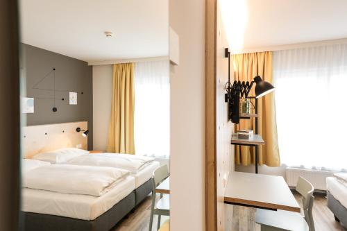 图尔恩Hotel Tullnerfeld的酒店客房设有两张床和一张桌子。