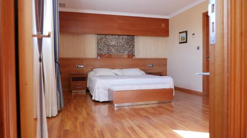 梅利利亚卢萨迪尔酒店的卧室配有白色的床,铺有木地板