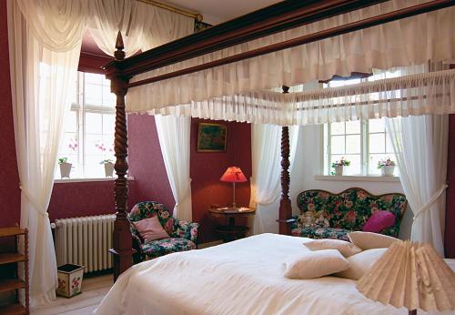 Gudme布罗霍姆城堡酒店的一间卧室配有一张天蓬床和两把椅子