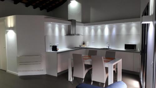 奥洛特Apartaments y Habitacions Entre Volcans的厨房配有白色橱柜和带椅子的柜台。
