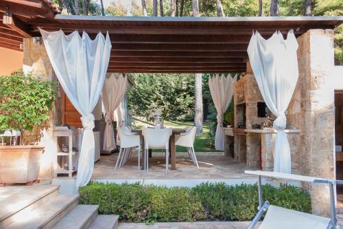 撒尼海滩Naftilos Villa Sani with private Pool的庭院配有白色窗帘和桌椅