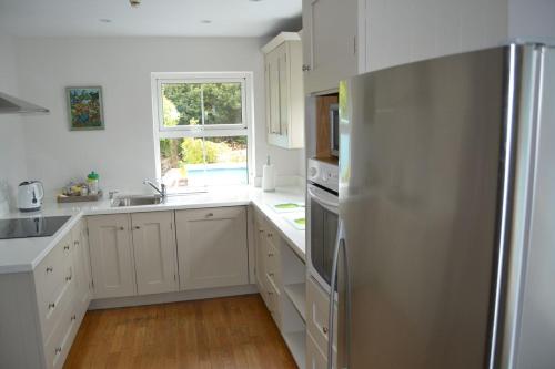 丁格尔Dingle Townhouse的厨房配有白色橱柜和不锈钢冰箱