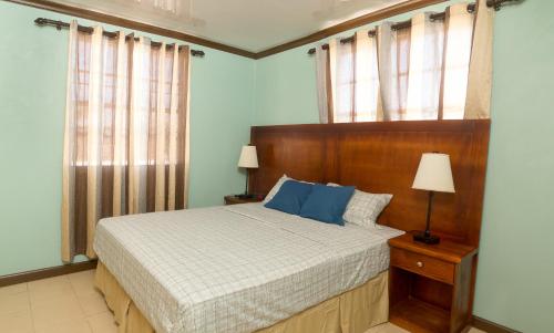 布里奇敦Believe Caribbean Apartment的一间卧室配有一张带木制床头板和窗户的床。