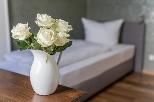 奥尔登堡Villa Stern的白色花瓶,上面有白色玫瑰,坐在桌子上