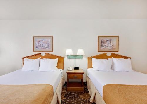 圣安吉洛Days Inn by Wyndham San Angelo的配有2盏灯的酒店客房的2张床