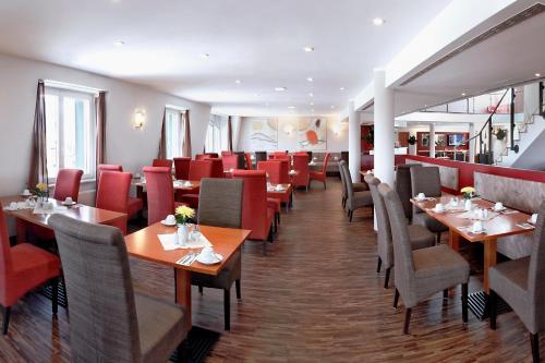 莱比锡H+莱比锡酒店的餐厅设有木桌和红色椅子