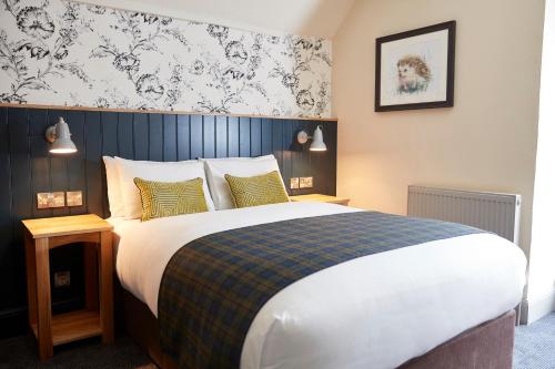 萨克斯特德Swan Hotel by Greene King Inns的一间卧室设有一张蓝色墙壁的大床
