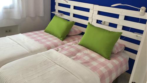 拉海瑞德拉Rosa Nautica 301的一间卧室配有两张带绿色枕头的床