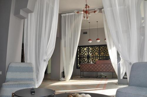 托隆阿尔特弥斯酒店的客厅配有白色窗帘和沙发