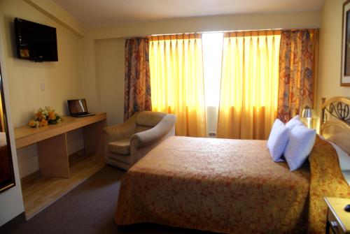 库斯科Hotel De la Villa Hermoza的配有一张床和一把椅子的酒店客房