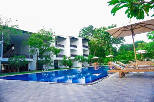 卡特勒格默Grand Tamarind Lake的酒店设有带椅子和遮阳伞的游泳池