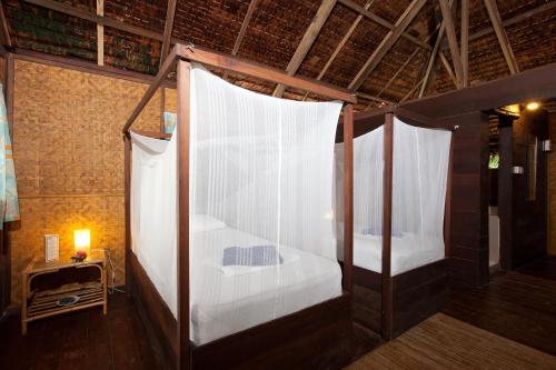 诗巫岛Rimba Resort - Dive Centre & Spa的配有白色窗帘的客房内的两张床