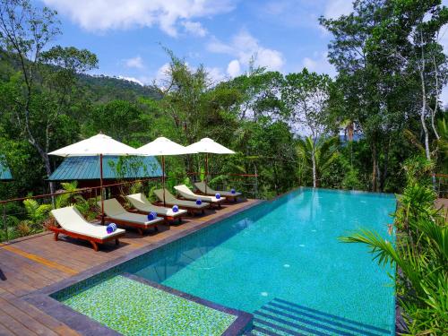 提喀迪尼拉马亚豆蔻俱乐部度假酒店的一个带躺椅和遮阳伞的游泳池