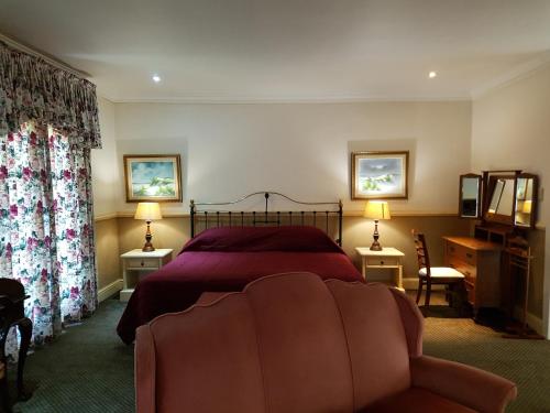 察嫩舍伍德乡间别墅酒店的一间卧室配有一张床、一张沙发和两盏灯。