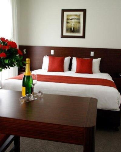 金皮玛丽河汽车旅馆的一间卧室配有一张床,桌子上放着一瓶葡萄酒