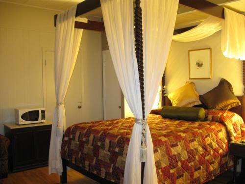 圣阿加瑟莫克莱尔蒙特汽车旅馆的一间卧室配有一张带窗帘和微波炉的天蓬床。