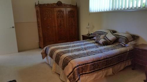 Ninderry山顶桃源旅馆的一间卧室配有一张床和一个木制橱柜