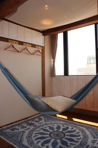 石垣岛guest house Holoholo Ishigakijima的带窗户的客房内的吊床