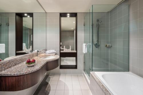 奥克兰奥克兰千禧大酒店的浴室配有2个盥洗盆、浴缸和淋浴。