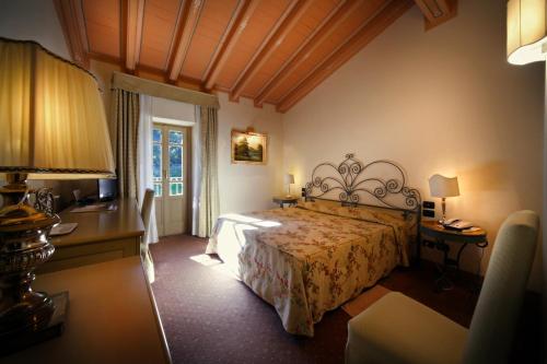伊塞奥黎莱斯米拉贝拉伊塞奥罗曼蒂克酒店的一间卧室配有一张床、一张书桌和一个窗户。