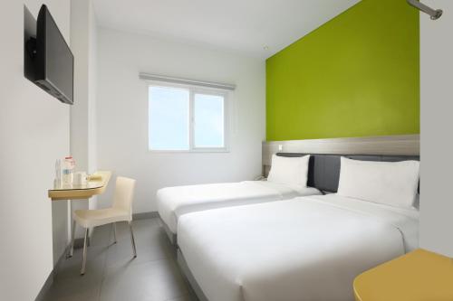 泗水爱玛瑞丝泗水马格雷酒店的绿墙旅馆客房的两张床