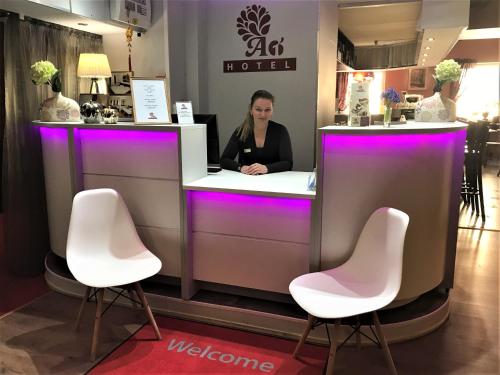 里加A1 Hotel Riga City Center的坐在柜台上的女士,带粉红色椅子