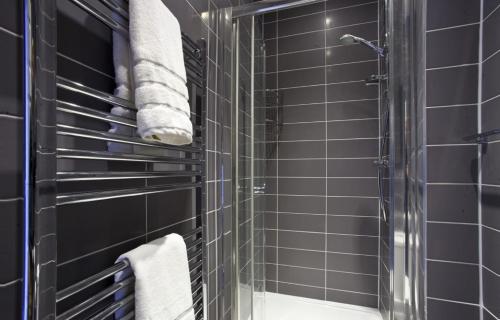 约克The Kings Apartment的浴室设有黑色瓷砖墙壁和淋浴。