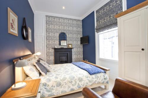 约克The Kings Apartment的一间卧室设有蓝色的墙壁、一张床和一张书桌
