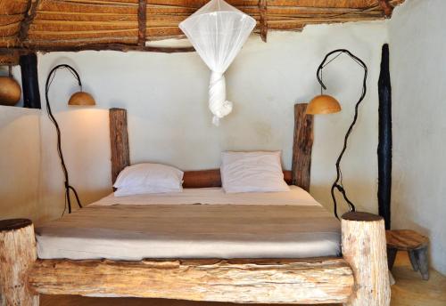 姆布尔Tama Lodge的一间卧室配有一张带两盏灯的木床。