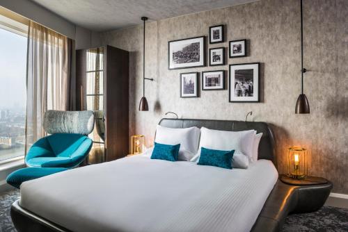 伦敦诺富特伦敦金丝雀码头酒店的一间卧室配有一张床和一张蓝色椅子
