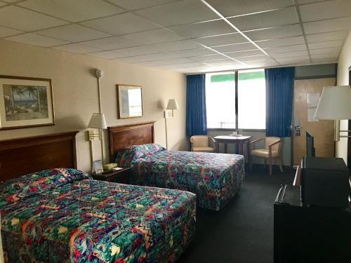 大洋城Tides Inn的酒店客房设有两张床和一张桌子。