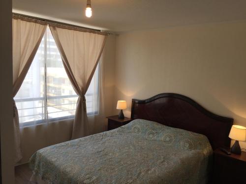 圣地亚哥Departamento Vergara的一间卧室配有一张床,窗户配有两盏灯。